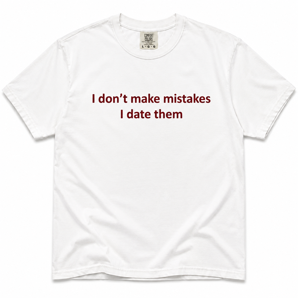 A white short-sleeve crewneck t-shirt with the text 'I don't make mistakes I date them' printed in dark red across the chest. The shirt is laid flat against a clean white background.