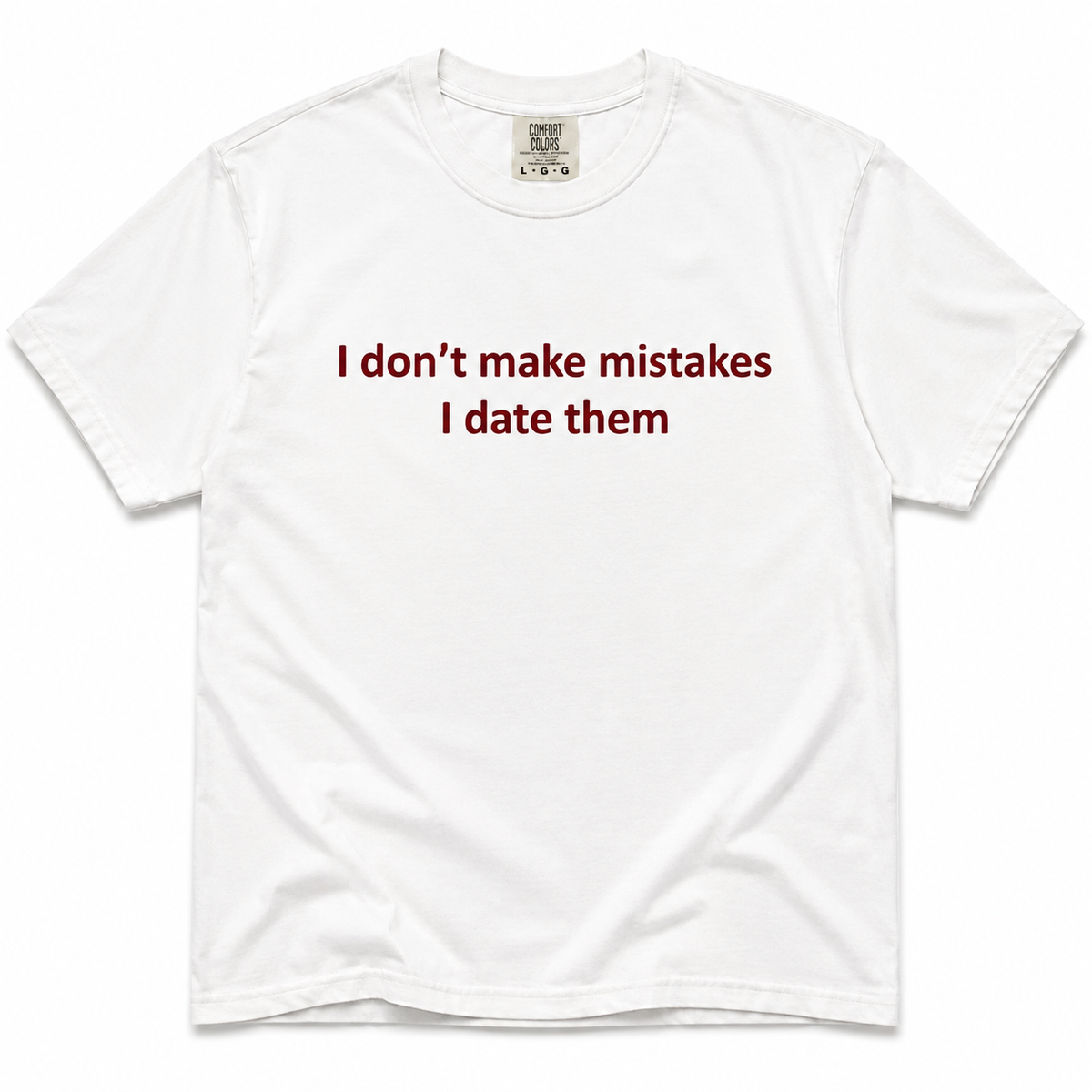 A white short-sleeve crewneck t-shirt with the text 'I don't make mistakes I date them' printed in dark red across the chest. The shirt is laid flat against a clean white background.