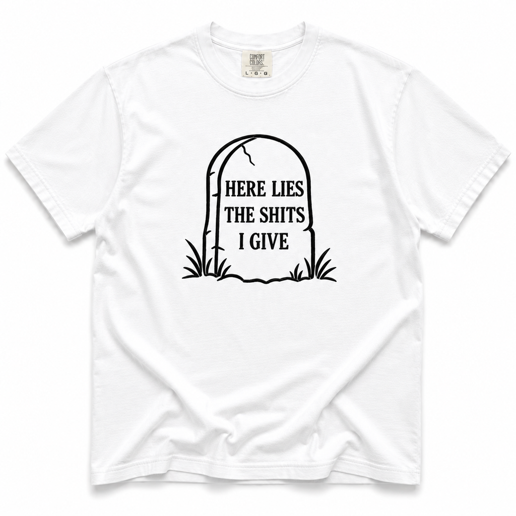 A white short-sleeve crewneck t-shirt with a black graphic of a tombstone on the chest containing the text 'HERE LIES THE SHITS I GIVE'.