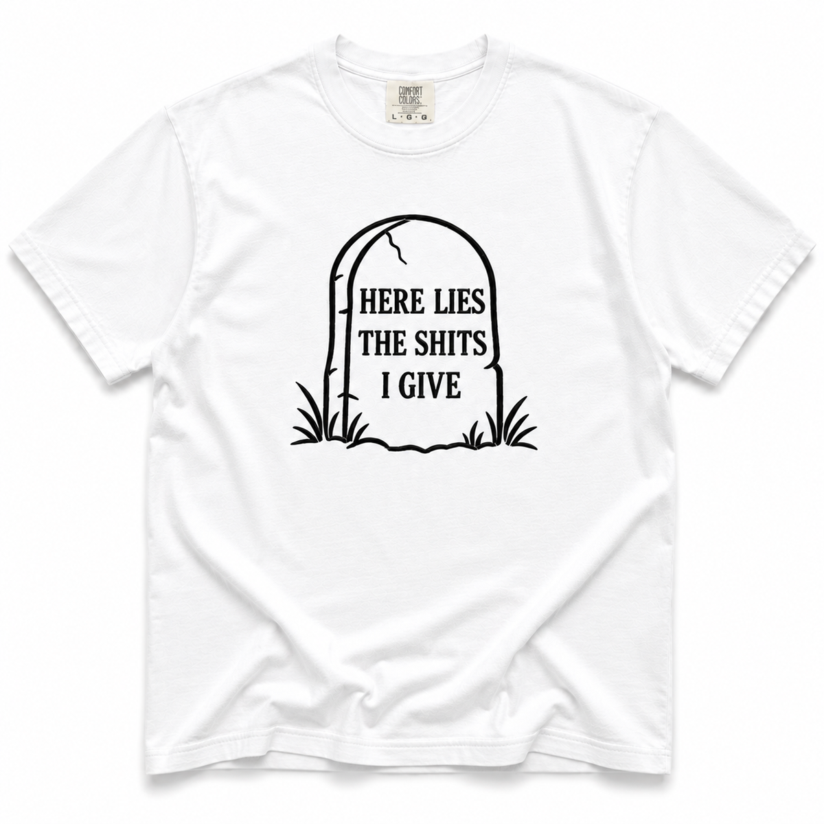 A white short-sleeve crewneck t-shirt with a black graphic of a tombstone on the chest containing the text 'HERE LIES THE SHITS I GIVE'.