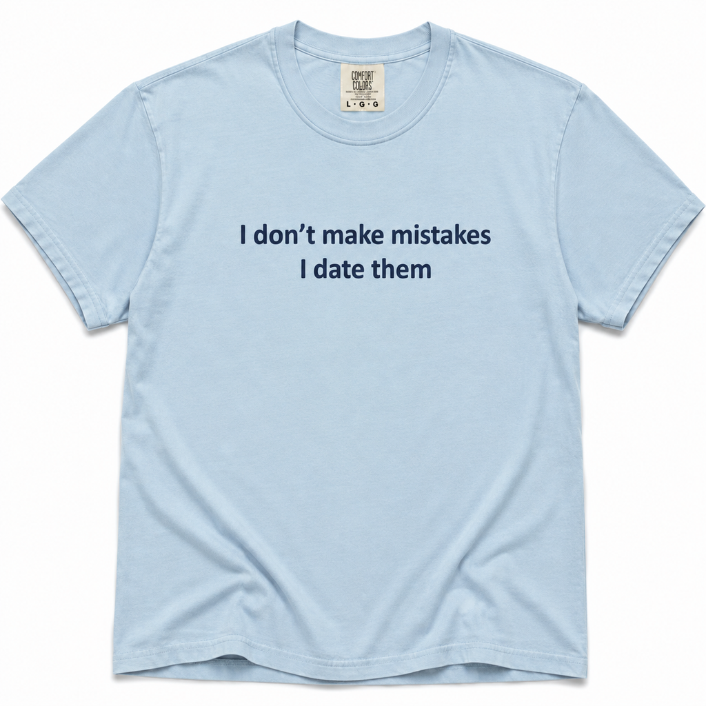 Chambray short-sleeve crewneck T-shirt with dark navy “I Don’t Make Mistakes, I Date Them” text printed across the chest on a white background.