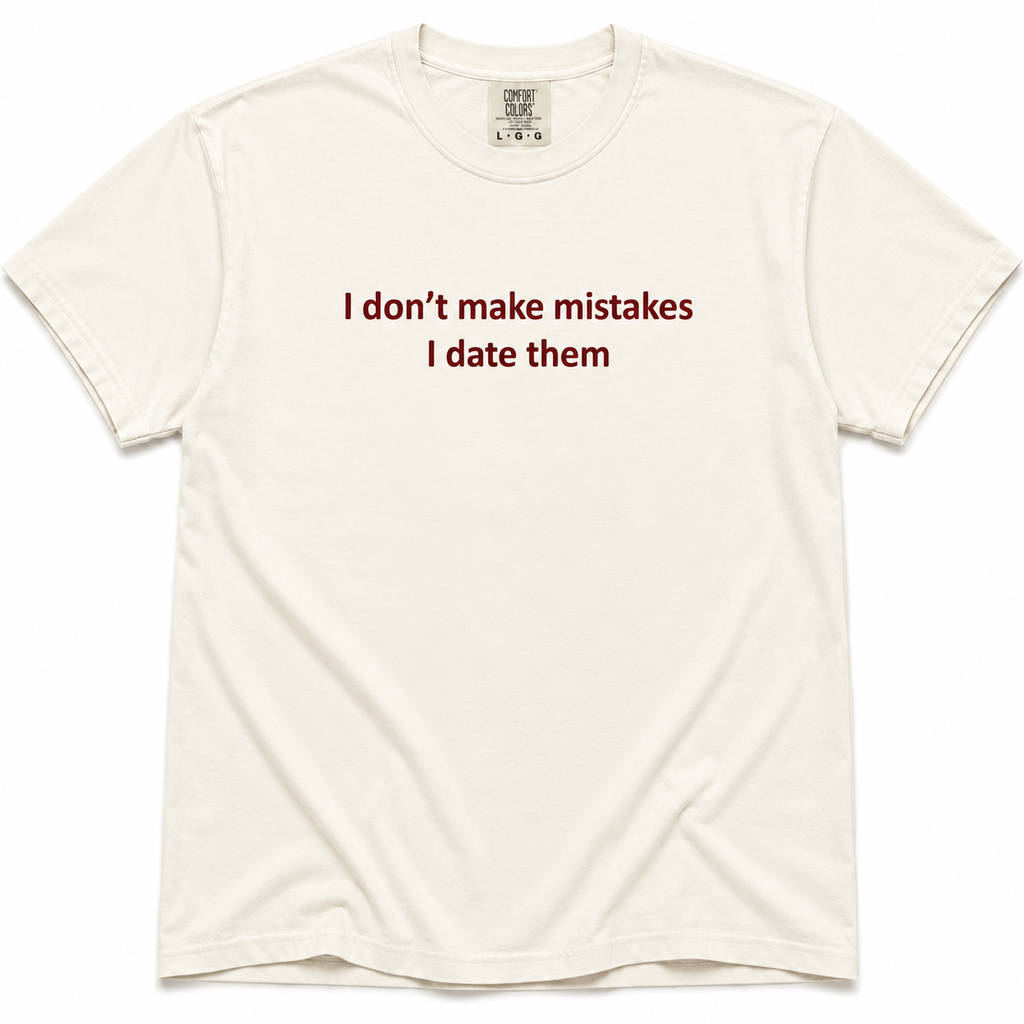 Ivory short-sleeve crewneck T-shirt with dark red “I Don’t Make Mistakes, I Date Them” text printed across the chest.