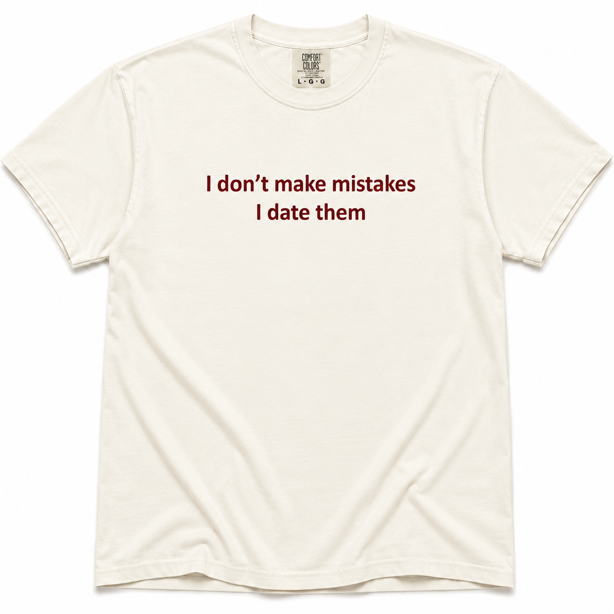 Ivory short-sleeve crewneck T-shirt with dark red “I Don’t Make Mistakes, I Date Them” text printed across the chest.
