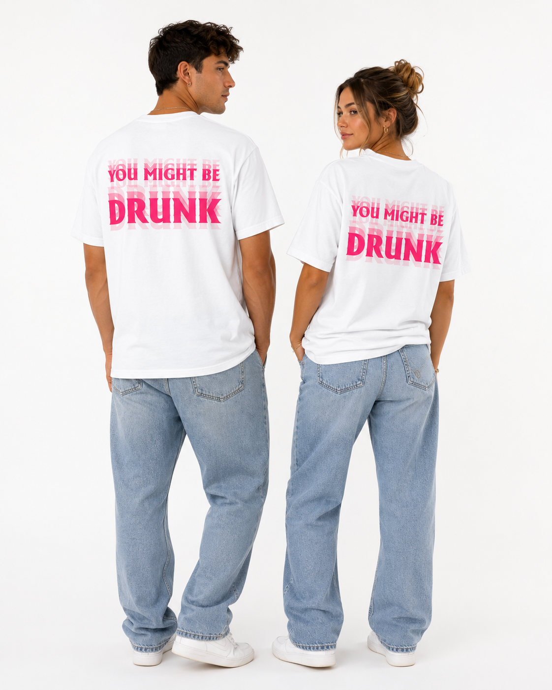 A man and a woman standing side by side, viewed from the back, wearing matching white t-shirts with a pink graphic text that reads 'YOU MIGHT BE DRUNK' and light blue jeans against a white studio background.