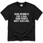 A black short-sleeve crewneck t-shirt with bold white text on the front reading 'DARK HUMOR IS LIKE A DAD. SOME PEOPLE DON'T HAVE ONE.