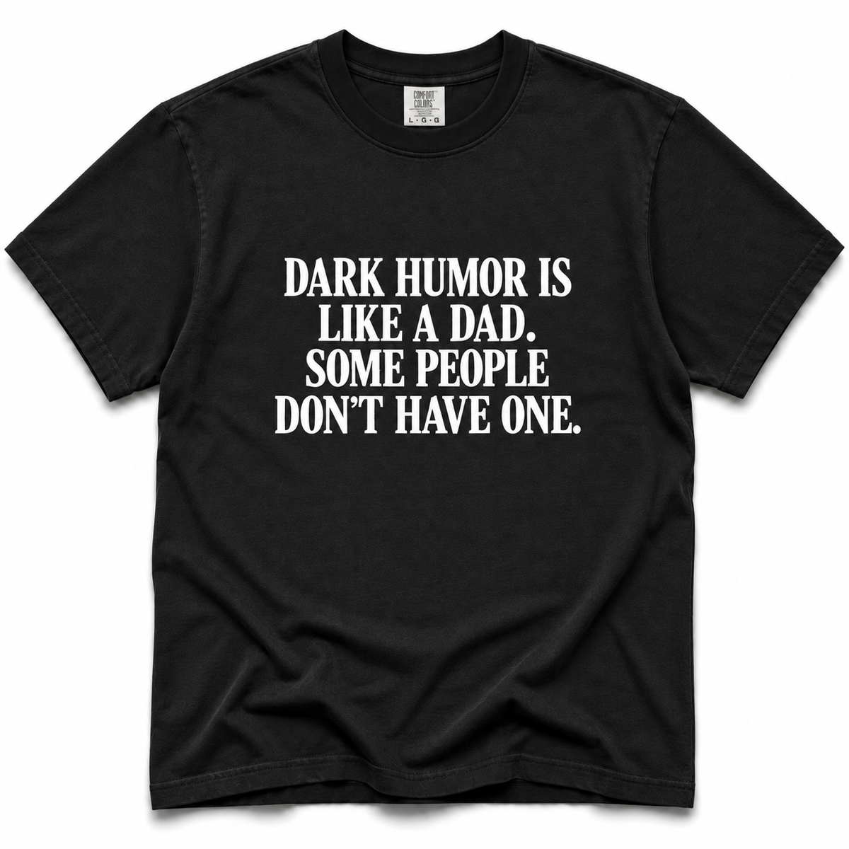 A black short-sleeve crewneck t-shirt with bold white text on the front reading 'DARK HUMOR IS LIKE A DAD. SOME PEOPLE DON'T HAVE ONE.
