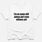 A white short-sleeve crewneck t-shirt with bold black text on the front reading 'I'm on some shit Jehovah ain't even witness yet', displayed against a light gray background.