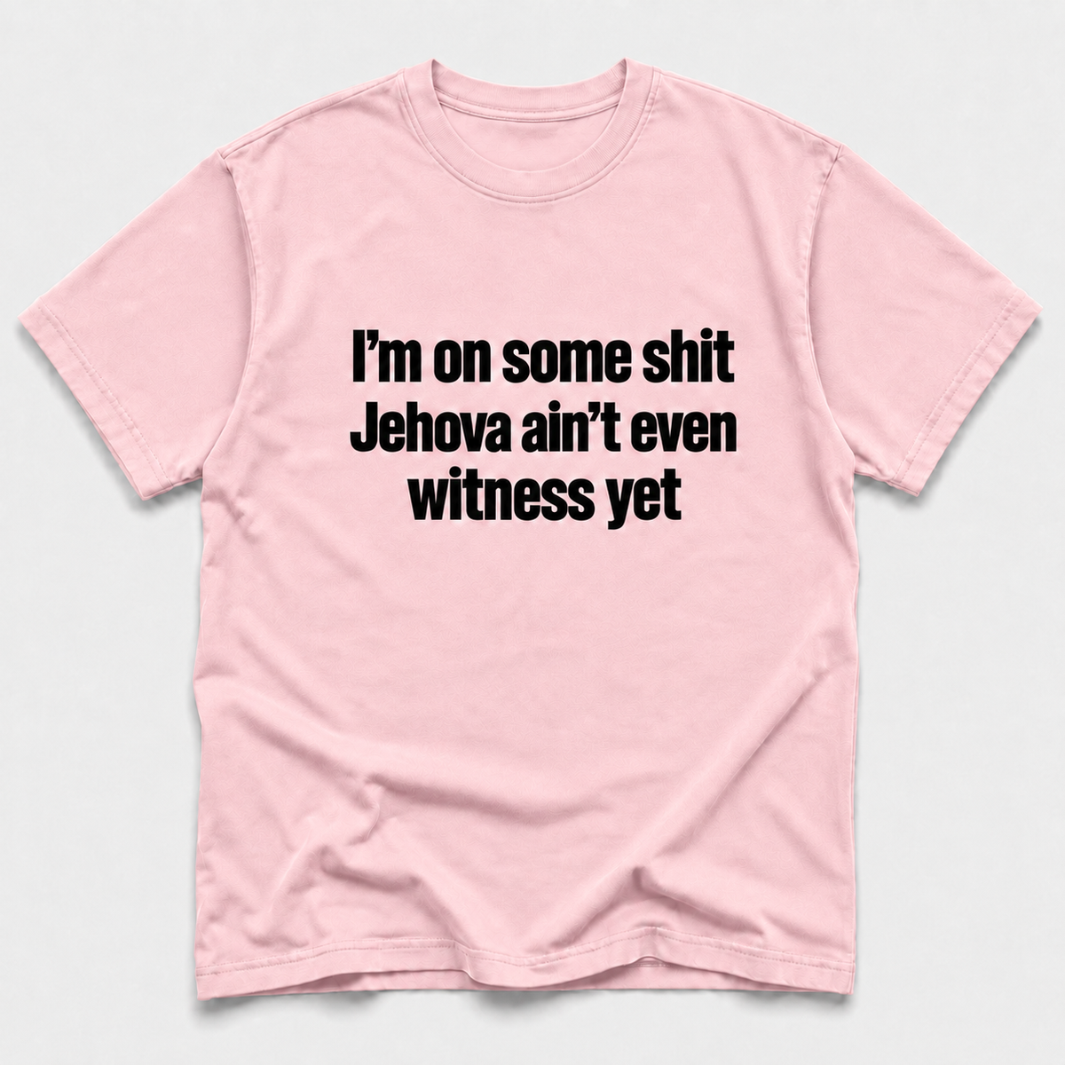 Blossom short-sleeve crewneck T-shirt with bold black text on the front reading “I’m on some shit Jehovah ain’t even witness yet,” displayed flat against a light gray background