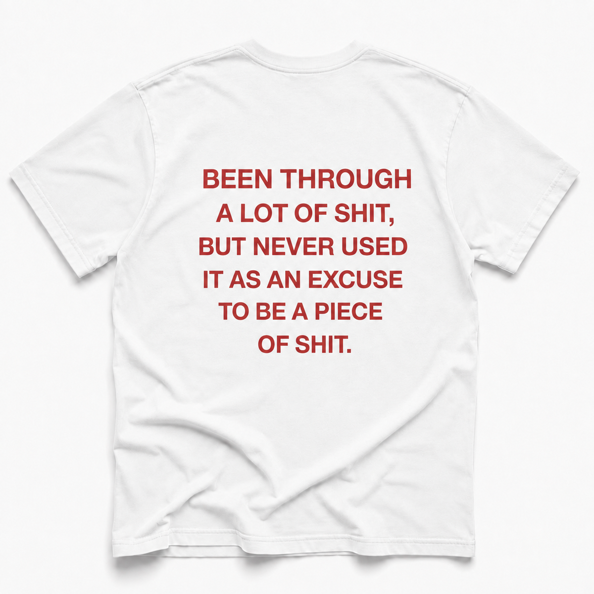 White short-sleeve t-shirt with bold red text printed on the back that reads, 'BEEN THROUGH A LOT OF SHIT, BUT NEVER USED IT AS AN EXCUSE TO BE A PIECE OF SHIT.'.