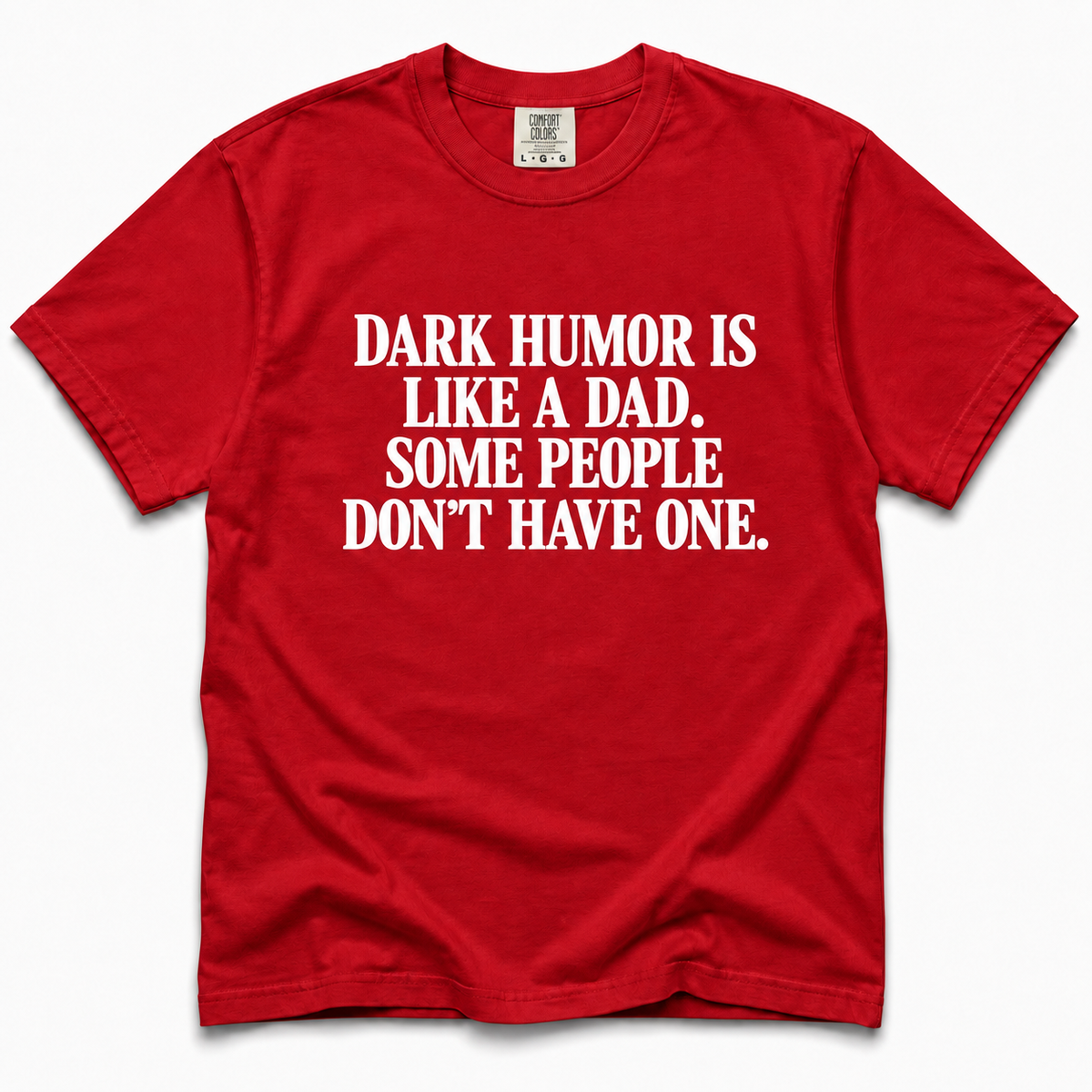 A red short-sleeve crewneck t-shirt with bold white text on the front that reads, 'DARK HUMOR IS LIKE A DAD. SOME PEOPLE DON'T HAVE ONE.