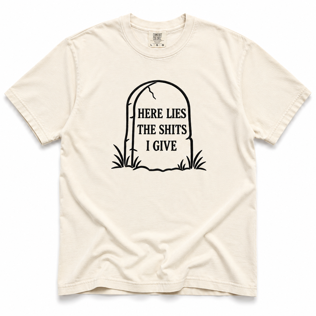 ivory crewneck t-shirt with a black graphic of a tombstone that reads 'HERE LIES THE SHITS I GIVE' on a plain white background.