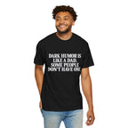 Male model wearing a black T-shirt with white “Dark Humor Is Like a Dad, Some People Don’t Have One” text on the front, paired with light blue jeans on a white background