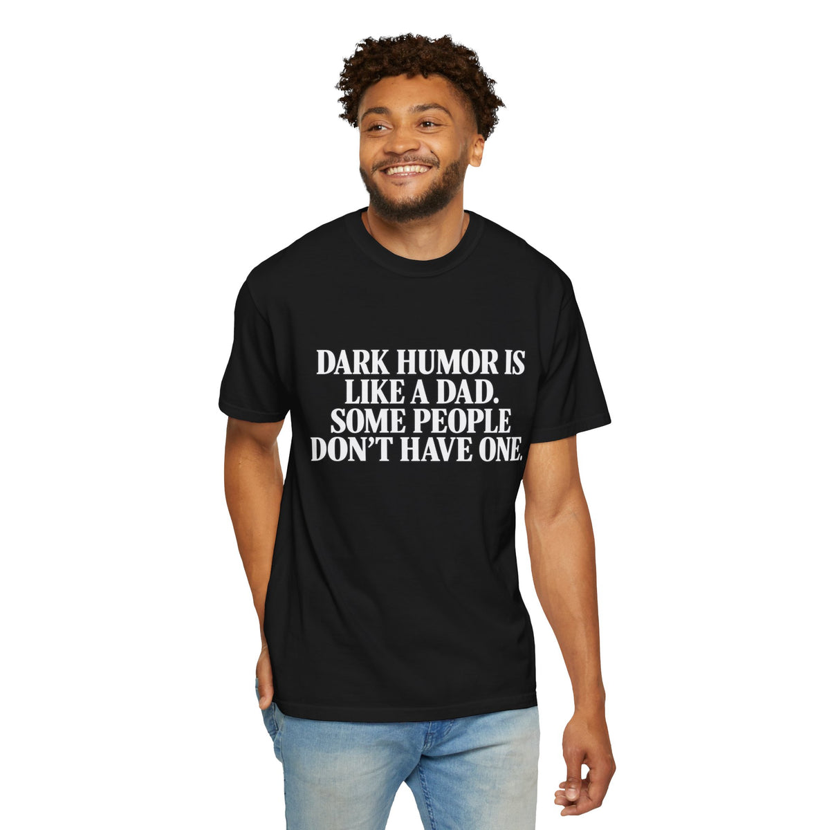 Male model wearing a black T-shirt with white “Dark Humor Is Like a Dad, Some People Don’t Have One” text on the front, paired with light blue jeans on a white background