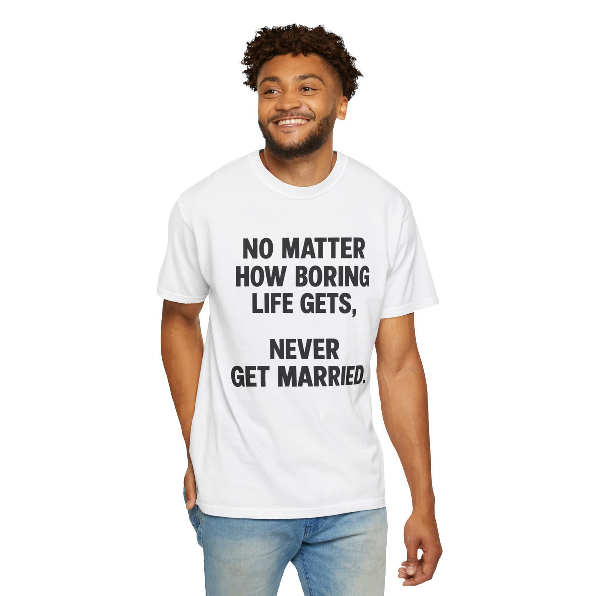 A man wearing a white crewneck t-shirt with black printed text that reads 'NO MATTER HOW BORING LIFE GETS, NEVER GET MARRIED.' paired with light blue jeans, set against a plain white background.
