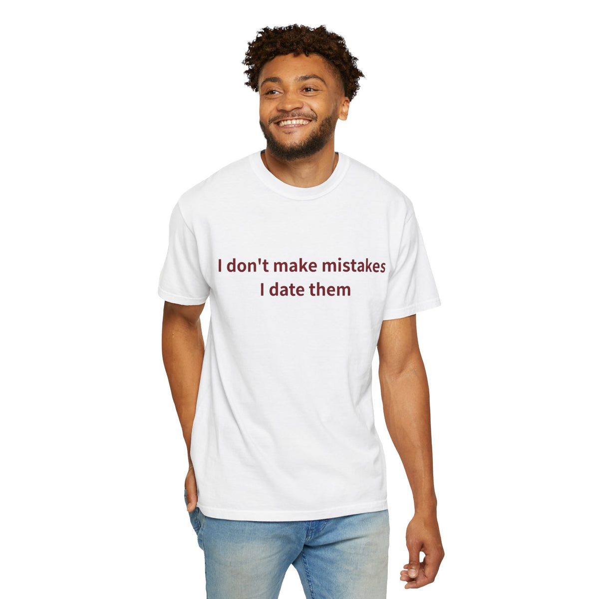 Male model wearing a white crewneck T-shirt with dark red “I Don’t Make Mistakes, I Date Them” text on the front, paired with blue jeans on a white background